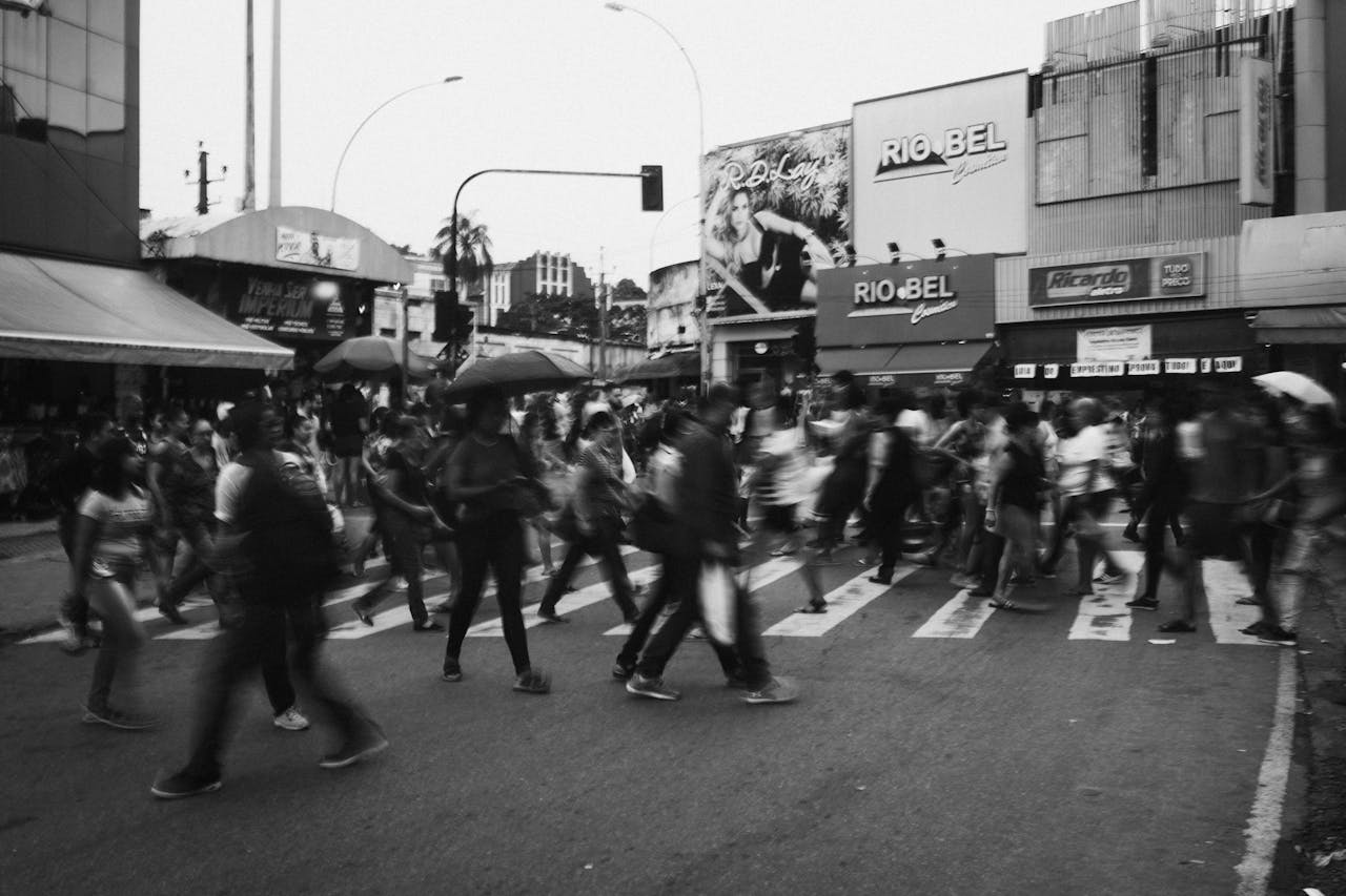 A bustling crosswalk in a city with blurred pedestrians, showcasing urban life.